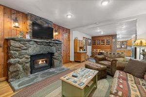 a living room with a stone fireplace with a tv at Grizzly Bear Creek- Mt Rushmore Views- Hot tub in Keystone