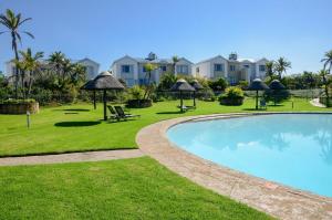a swimming pool with umbrellas in a yard with houses at Pinnacle Golf Estate Haven in Mossel Bay