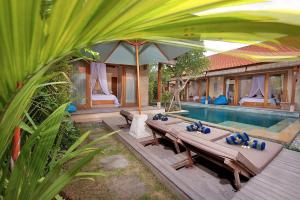un complejo con piscina, mesa y sombrilla en The Tamantis Villa, en Canggu