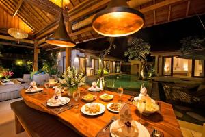 un comedor con una mesa con comida y una piscina en The Tamantis Villa, en Canggu