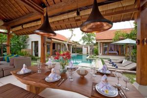 una mesa de comedor en una villa con piscina en The Tamantis Villa, en Canggu