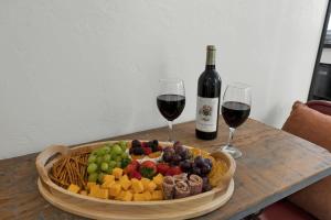 a tray of fruit on a table with two glasses of wine at Rojo-Charming unit walking distance to Main St! in Fredericksburg
