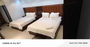two beds in a hotel room with white sheets and pillows at Park Amaira Banani Guesthouse in Dhaka