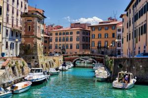 a group of boats docked in a canal with buildings at Mono perfetto per Ospedale e Treni Check-in rapido in Livorno