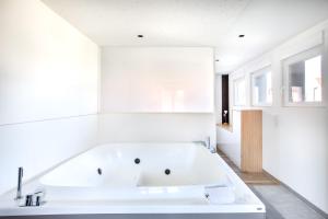 a large white bath tub in a white bathroom at Gite Spa L'Atelier Emile - Spa Privatif - 5 min COLMAR in Sainte-Croix-en-Plaine +46 photos