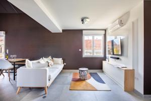 a living room with a white couch and a table at Gite Spa L'Atelier Emile - Spa Privatif - 5 min COLMAR in Sainte-Croix-en-Plaine