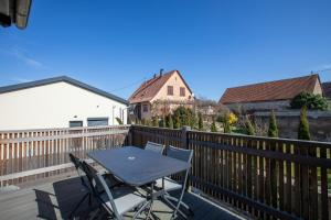 a table and chairs on a deck with a fence at Gite Spa L'Atelier Emile - Spa Privatif - 5 min COLMAR in Sainte-Croix-en-Plaine