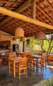 a restaurant with wooden tables and chairs and lamps at Vila Alta Caraíva in Caraíva