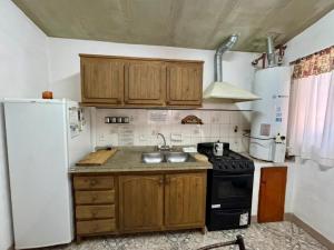 a kitchen with wooden cabinets and a white refrigerator at La Pantera in San Antonio de Arredondo +2 photos