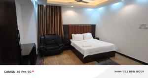 a bedroom with a bed and a black chair at Park Amaira Banani Guesthouse in Dhaka