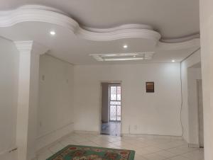 a room with white walls and a ceiling with a rug at Hotel quarto 01 in Montes Claros