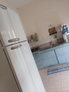a white refrigerator in a kitchen with blue cabinets at Hotel quarto 01 in Montes Claros