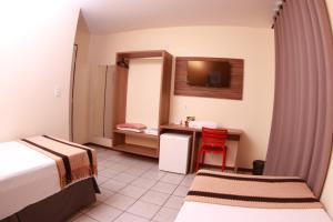 a room with two beds and a desk with a television at Boulevard Park Hotel in São Luís