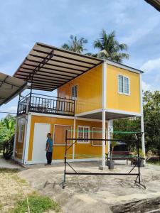 a woman standing in front of a yellow house at CTZ PAROH RIVER PARK in Jertih