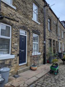 a brick house with a black door and a potted plant at Heart of Hebden in Hebden Bridge