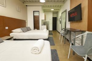 a hotel room with two beds and a table and a television at Malibu loft hotel in Medellín