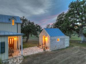 a small stone shed with a blue roof next to a house at 7Cs Sunset Valley Ranch in Fredericksburg