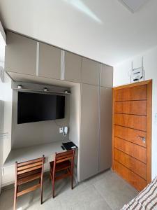 a bedroom with a desk with two chairs and a tv at Smart Studio Lavras in Lavras