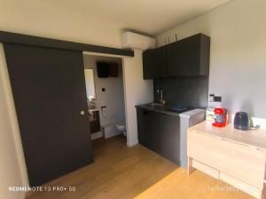 a small kitchen with black cabinets and a counter top at Tiny House, 12mn du Parc, Terrasse & Clim in Châteaumur