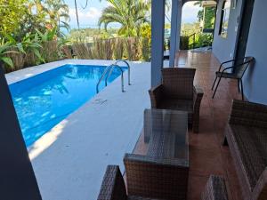 a swimming pool with wicker chairs and a table at Hotel Manuel Antonio Beracha in Quepos