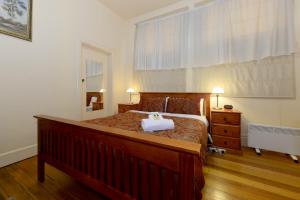 a bedroom with a large bed with a wooden bed frame at Edinburgh Gallery Bed & Breakfast in Hobart