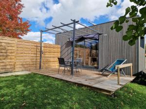 a patio with a table and chairs on a wooden deck at Tiny House, 12mn du Parc, Terrasse & Clim in Châteaumur