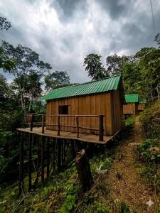a wooden building with a green roof on a hill at Cabañas Kapuy in Florencia