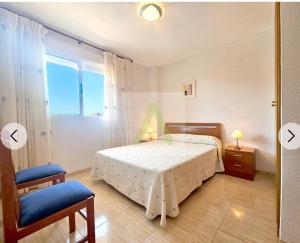 a bedroom with a bed and a chair and a window at Beachfront apartment in Oropesa del Mar