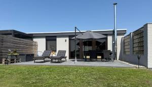 a group of chairs and an umbrella in front of a building at Ferienwohnung-Maren in Marienleuchte