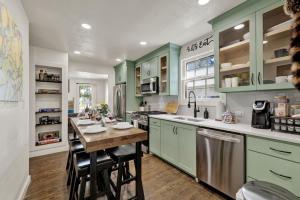 a kitchen with green cabinets and a wooden table at Southern Charm - Near Main With Hot Tub in Fredericksburg +8 photos