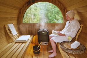 a man sitting in a sauna reading a book at B&Biotope in Heusden
