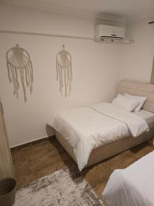 two beds in a room with white walls at Modern 3BR Apartment - Heart of Sheikh Zayed - Gated Compound in Sheikh Zayed