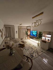a living room with a couch and a tv at Modern 3BR Apartment - Heart of Sheikh Zayed - Gated Compound in Sheikh Zayed