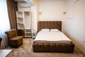 a bedroom with a large bed and a chair at Jolie Boutique Hotel in Craiova