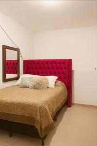a bed with a red headboard in a room at Casa en Paseo San Junipero in San José el Alto +21 photos