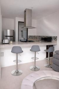 a kitchen with three bar stools and a counter at Casa en Paseo San Junipero in San José el Alto