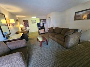 a living room with two couches and a tv at Merrimac Inn and Suite in Williamsburg