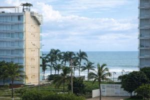 a view of the ocean and a building and palm trees at Estudio compacto en Riviera Diamante con alberca in Acapulco