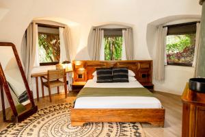 a bedroom with a bed and a table and windows at Bambuda Lodge in Bocas Town