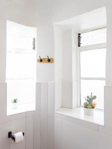 a white bathroom with a toilet paper roll and two windows at Illa B&B in Cusco +125 photos