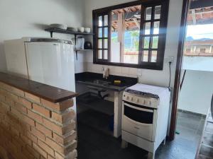 a kitchen with a stove and a sink at Pousada e Chalés Santorini in Caraguatatuba