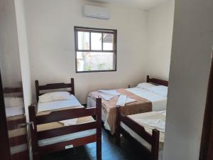 a room with two beds and a window at Pousada e Chalés Santorini in Caraguatatuba