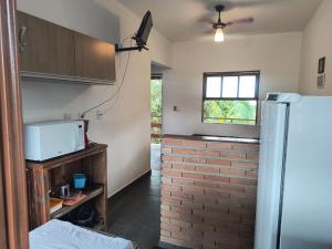 a kitchen with a refrigerator and a brick wall at Pousada e Chalés Santorini in Caraguatatuba +15 photos
