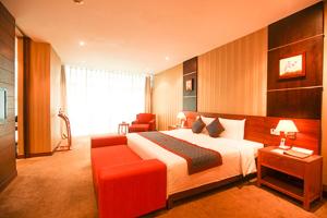 een hotelkamer met een bed en een rode bank bij Petro Hotel in Vung Tau