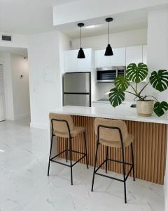 a kitchen with two stools and a counter with a refrigerator at Beautiful House Near Marlins Stadium in Miami