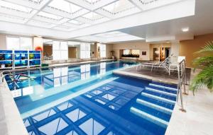 a large pool with blue water in a building at Flat em Alphaville - Super Novo in Barueri
