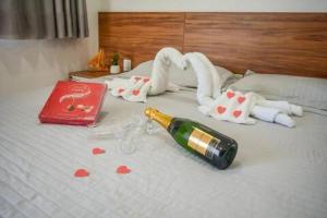 a bottle of champagne and hearts on a bed at Pousada Posto Elite in Água Boa