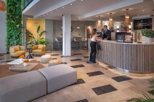 a man and woman standing at a bar in a lobby at Hotel SERHS Del Port in Barcelona
