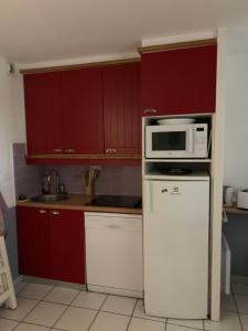 a kitchen with red cabinets and a microwave on a refrigerator at L escale Oceane in Moliets-et-Maa