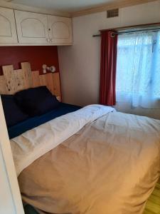 a bedroom with a bed and a red curtain at mobile home in Bielle
